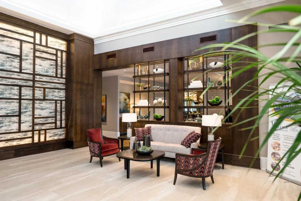 Lounge area with a sofa and armchairs in front of a stone-and-wood accent wall with glass shelving