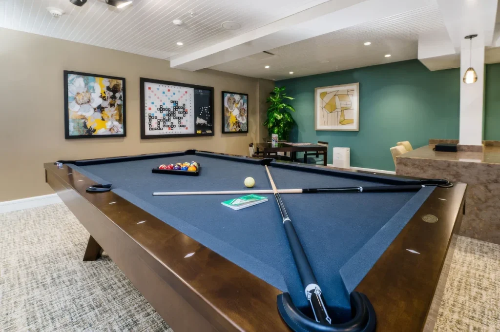 Game room with a blue-felt pool table, framed art on the walls and a teal accent wall