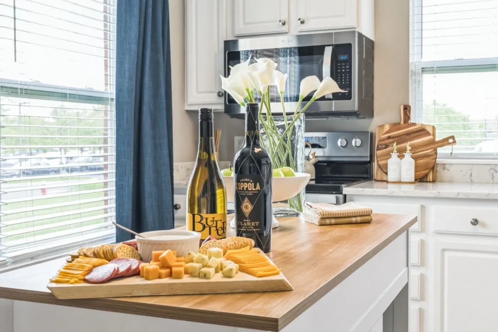 Kitchen counter with two wine bottles and a charcuterie board in front of a bright window