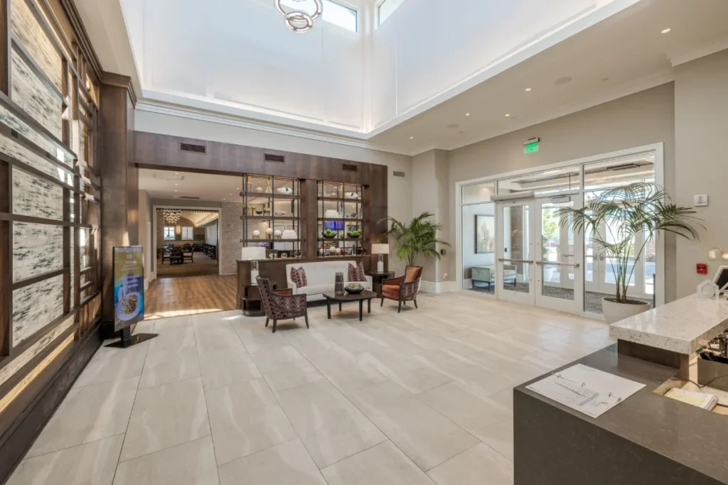 Spacious building lobby with high ceilings, tile floors, a seating area and a front desk