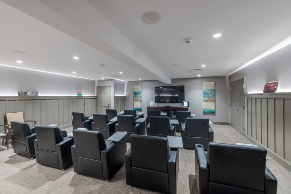 Movie room with rows of black leather recliners facing a wall-mounted TV