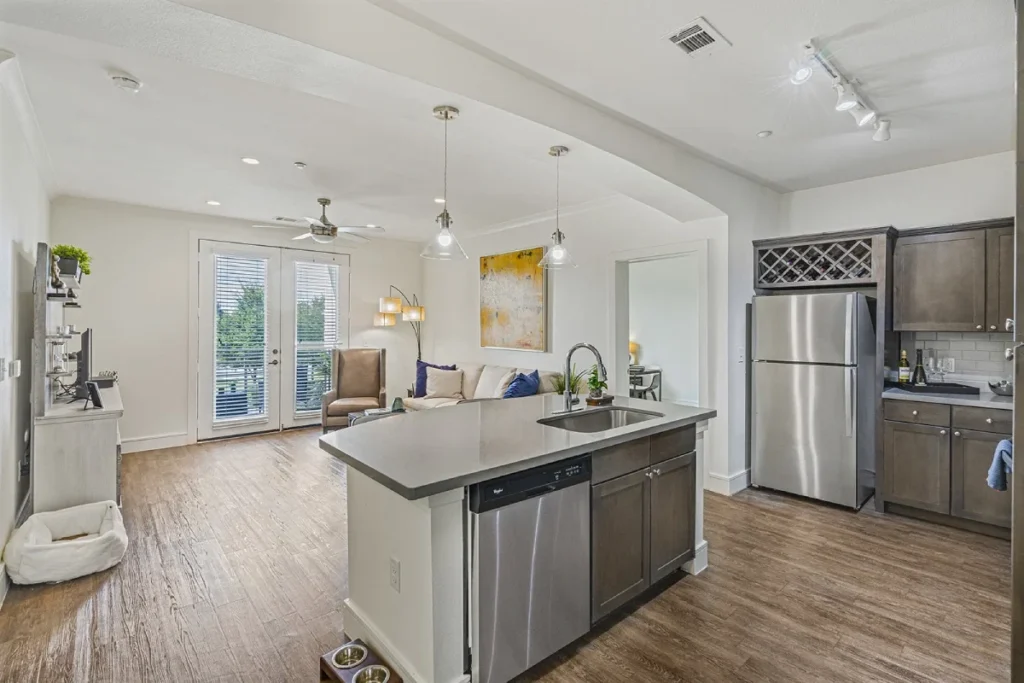 Open apartment living and kitchen area with an island, a sofa and French doors