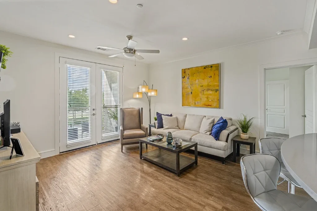 Living room with a light sofa, a yellow abstract painting, a ceiling fan and French doors