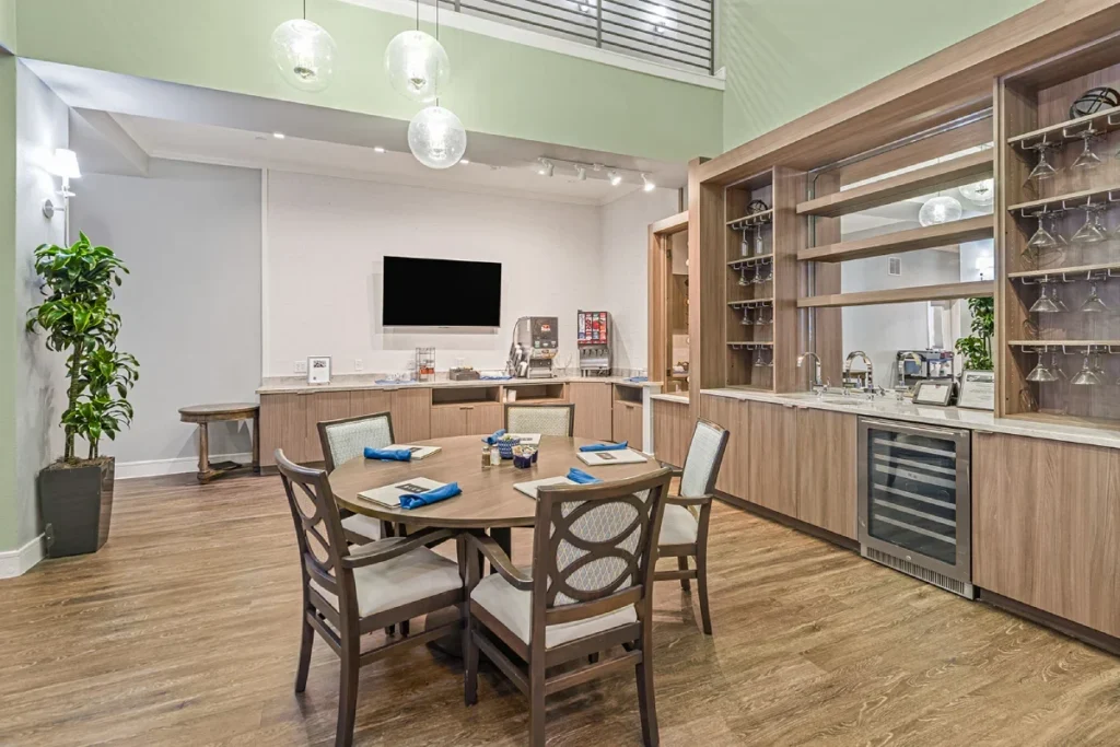 Kitchenette and dining area with a round table, wooden cabinets, a wine fridge and a wall-mounted TV