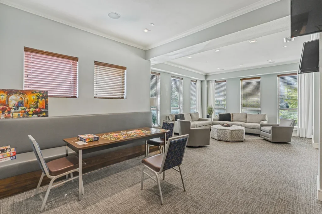 Lounge with a long table with a game board, sofas in the background and wall-mounted TVs