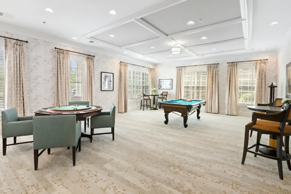 Bright game room with a pool table, card tables and large windows