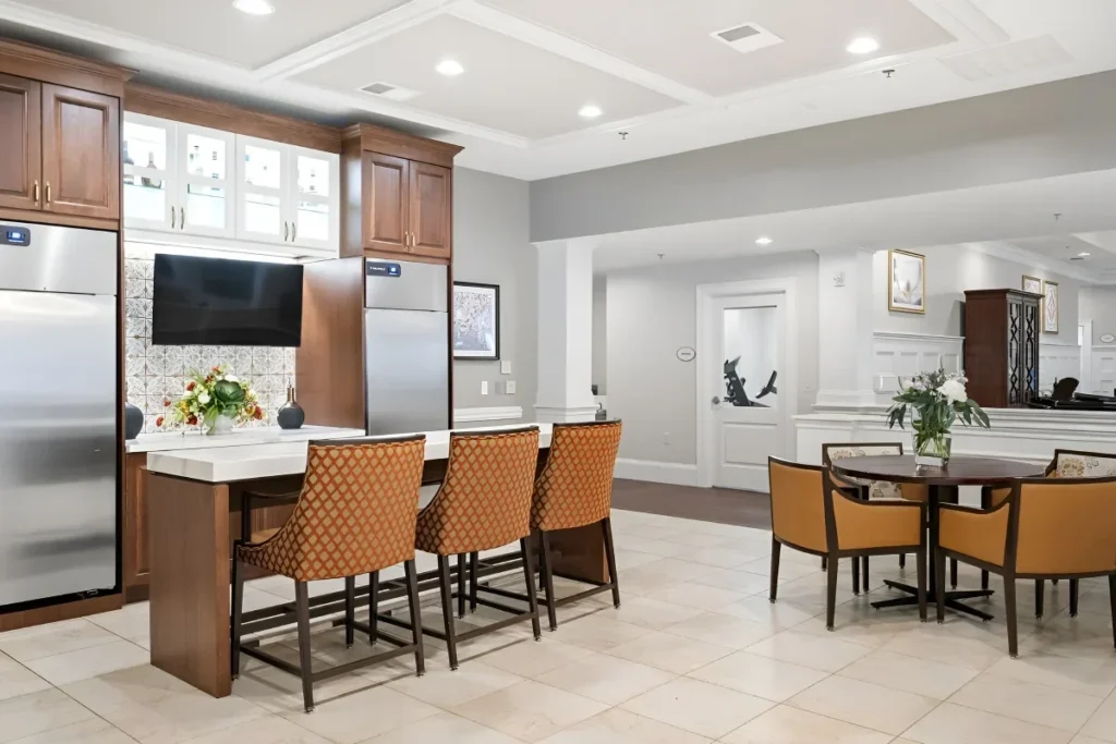 Kitchenette with a counter with cushioned stools, wooden cabinets and a wall-mounted TV