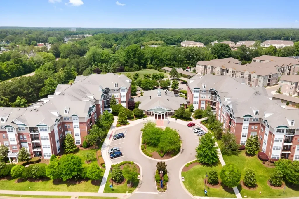 Aerial view of brick apartment buildings around a landscaped courtyard, with wooded surroundings