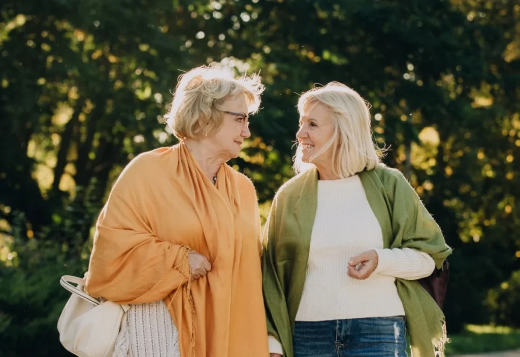Two senior women walking and talking together in a park