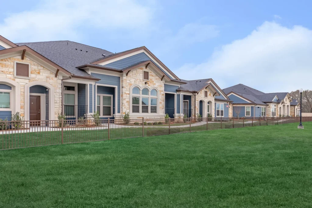 Row of cottage-style homes with stone and siding fronting a green lawn