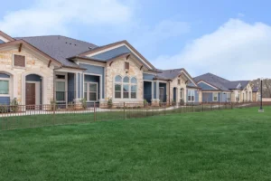 Row of cottage-style homes with stone and siding fronting a green lawn