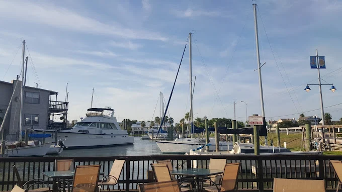 Boats docked at a marina with sailboat masts behind a railing