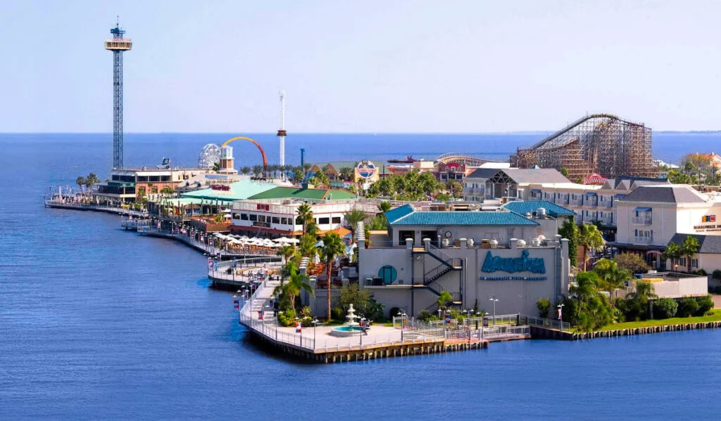 Aerial view of a waterfront boardwalk with an observation tower and roller coaster