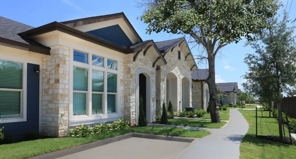 Cottage-style home with a stone exterior and a sidewalk through a green lawn