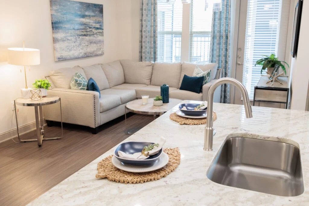 Apartment living room with a sectional sofa and a kitchen sink in the foreground
