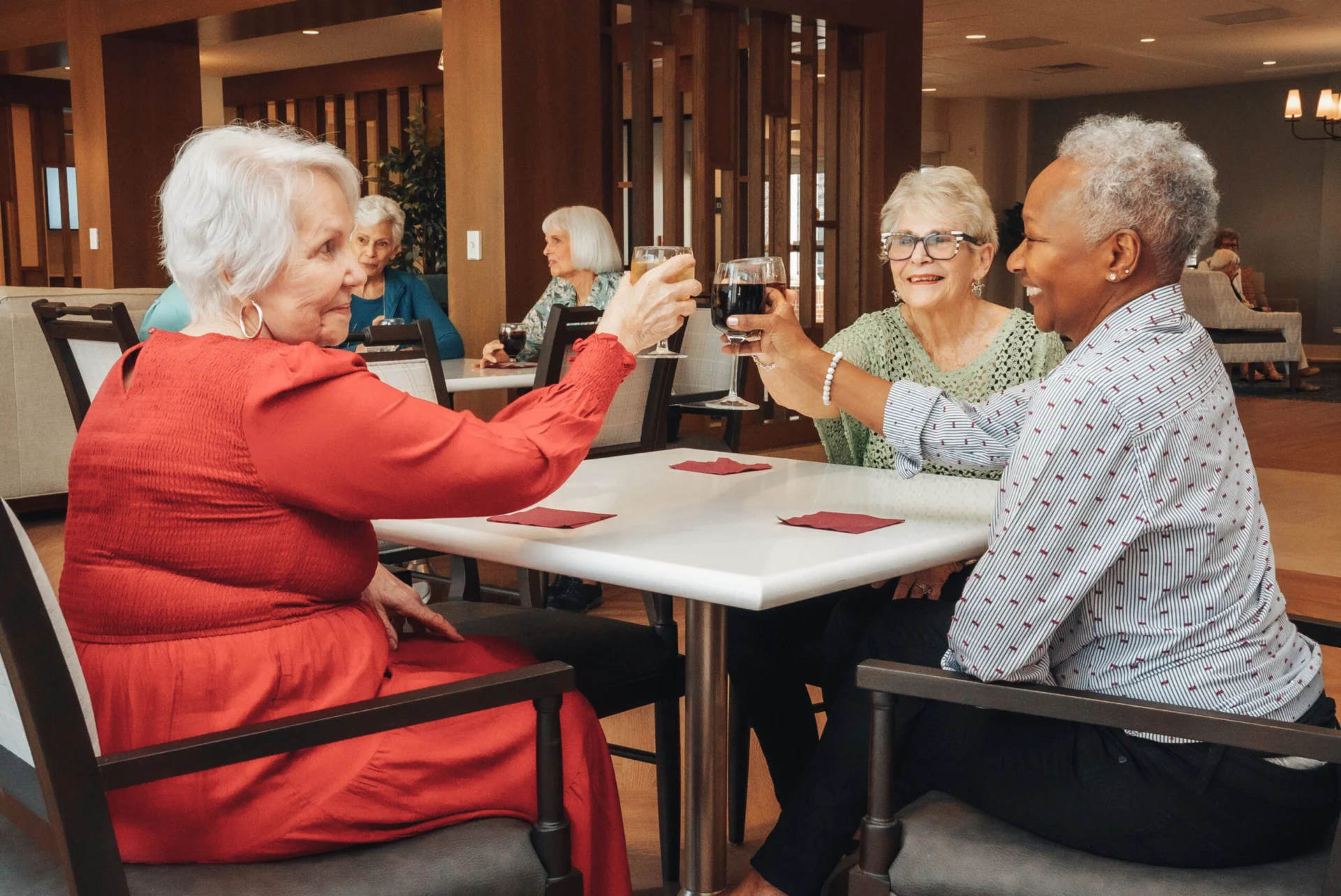 Seniors toasting with drinks while playing cards at a table