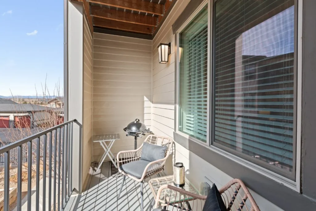Apartment balcony with two chairs and a small table overlooking nearby buildings