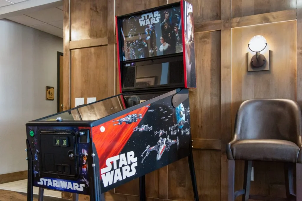 Pinball machine with a bar stool and a wall-mounted TV in a game room