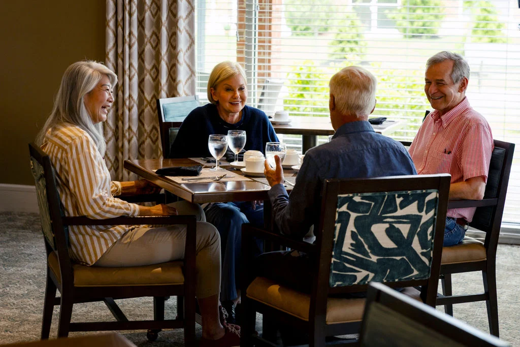 Group of seniors chatting over drinks at a dining table