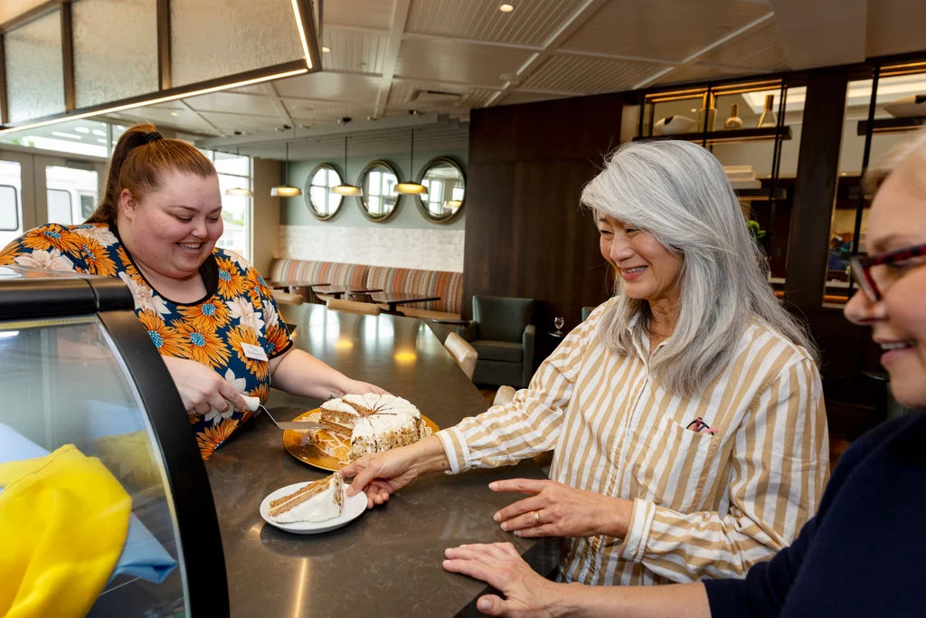 Senior woman and man chatting with a staff member at a cafe counter