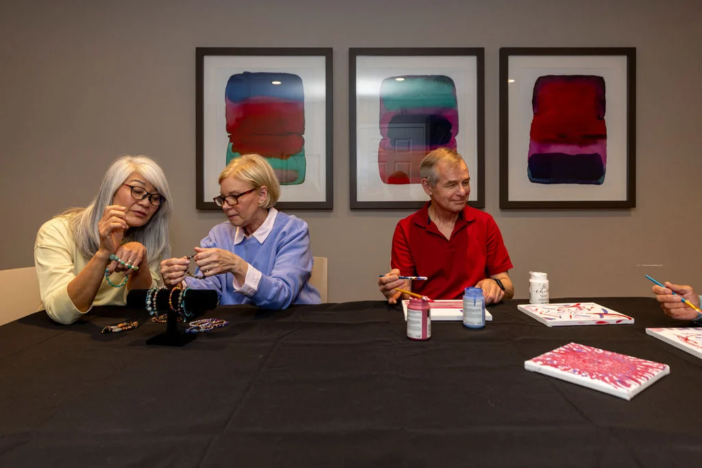Three seniors making jewelry crafts at a table