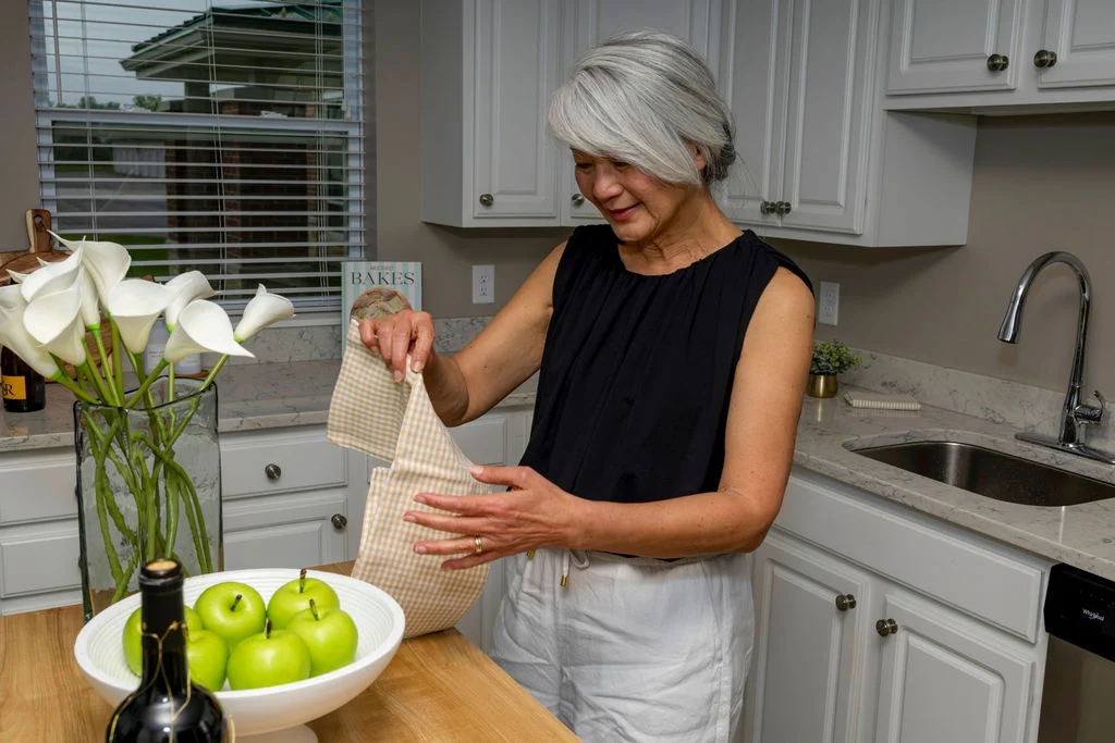 Senior woman unpacking groceries in a kitchen beside a bowl of green apples