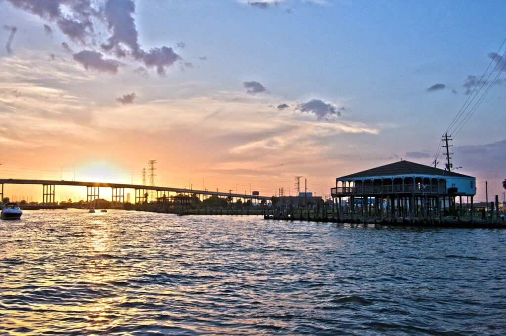 Sunset over a bay with a bridge and a waterfront building
