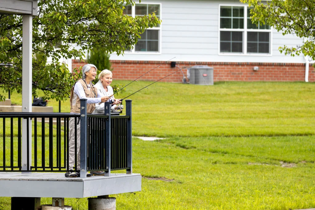 Two seniors on an observation deck beside a green lawn