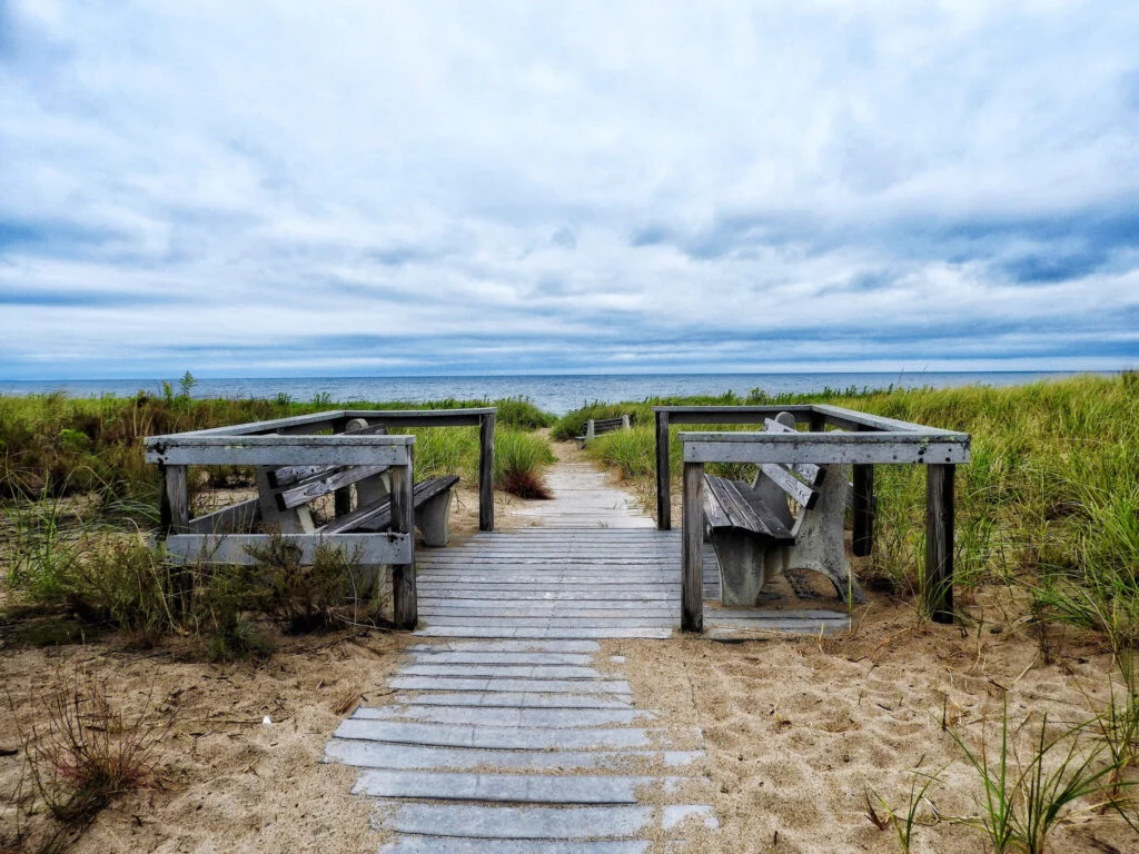 Wooden boardwalk path leading to shaded seating areas near the beach