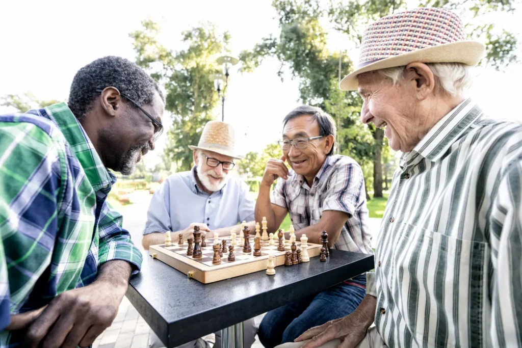 Senior men playing chess outside together